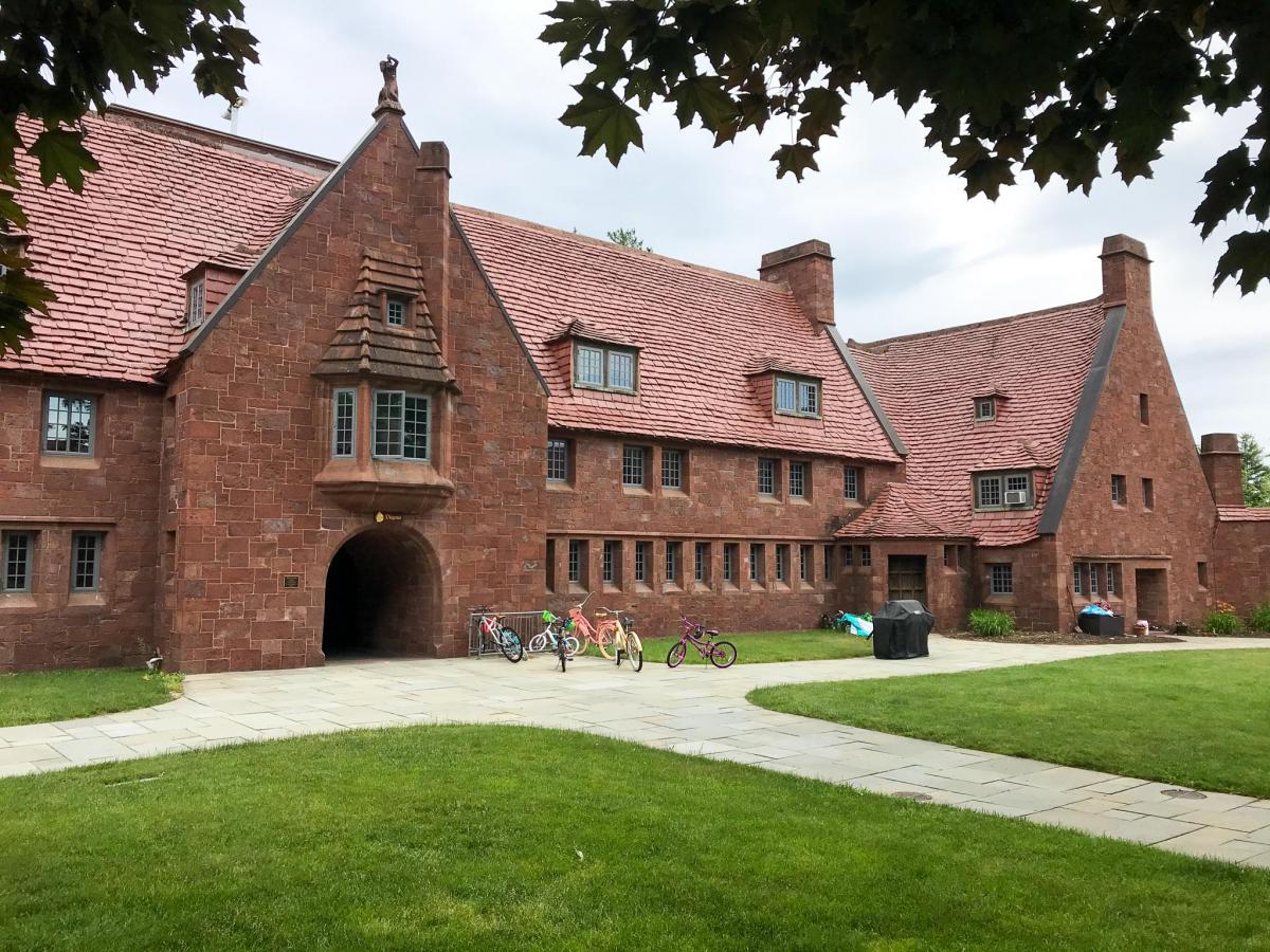 Historic brick building with grass and trees in background
