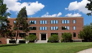 Front view of brick building with trees and grass in front